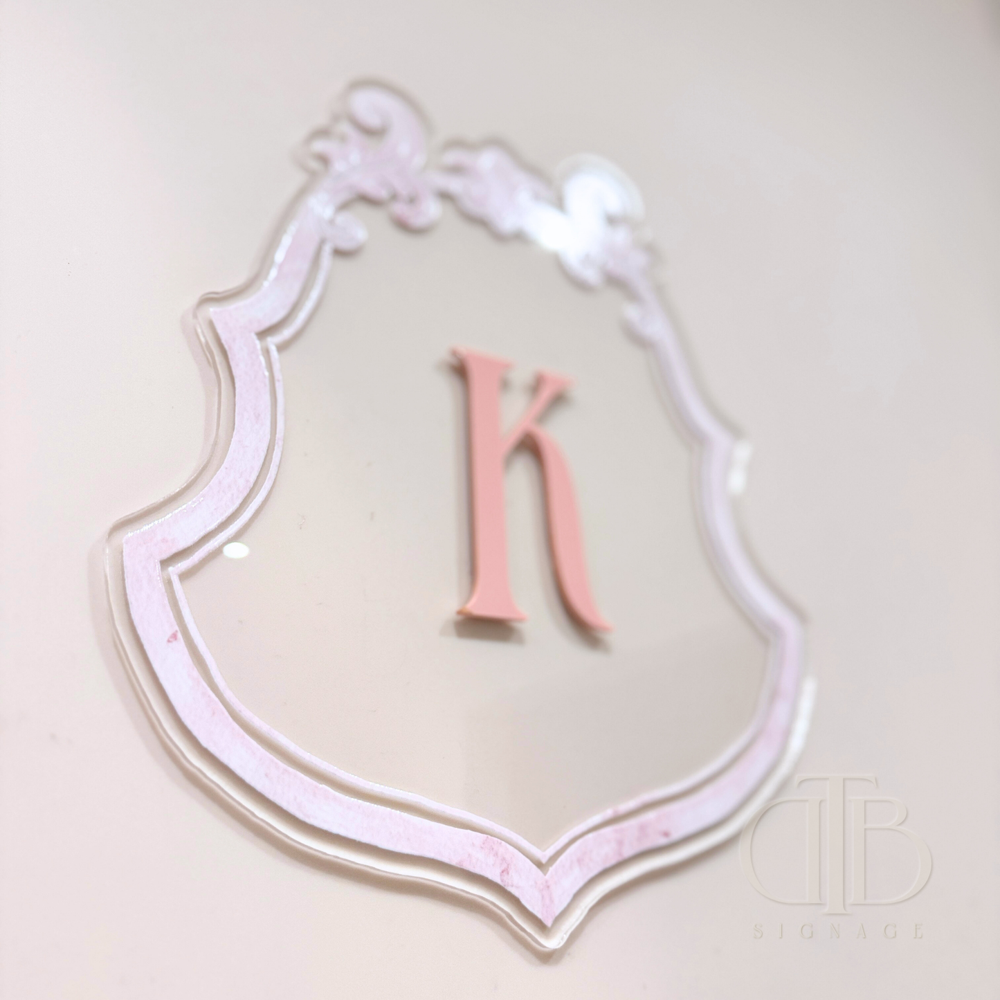 Luxury crest with baby pink frame UV printed and acrylic initial K in baby pint, close up view from the bottom