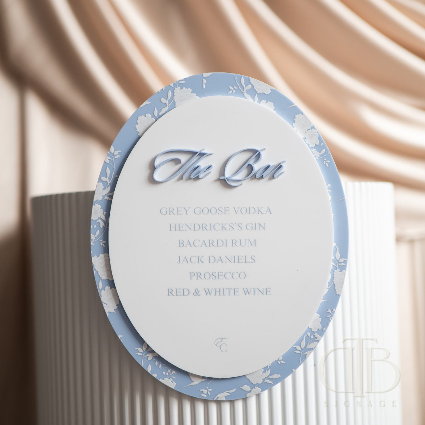 Round cocktail menu with blue decorative border and white text against a neutral background