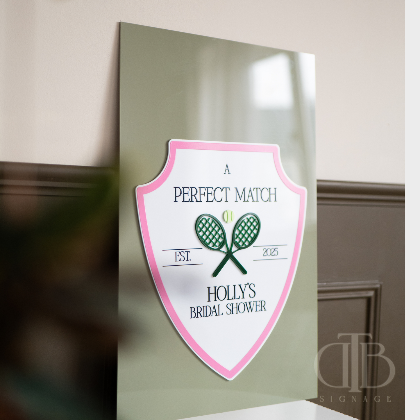 Decorative sign for a bridal shower with tennis racket design on a green background