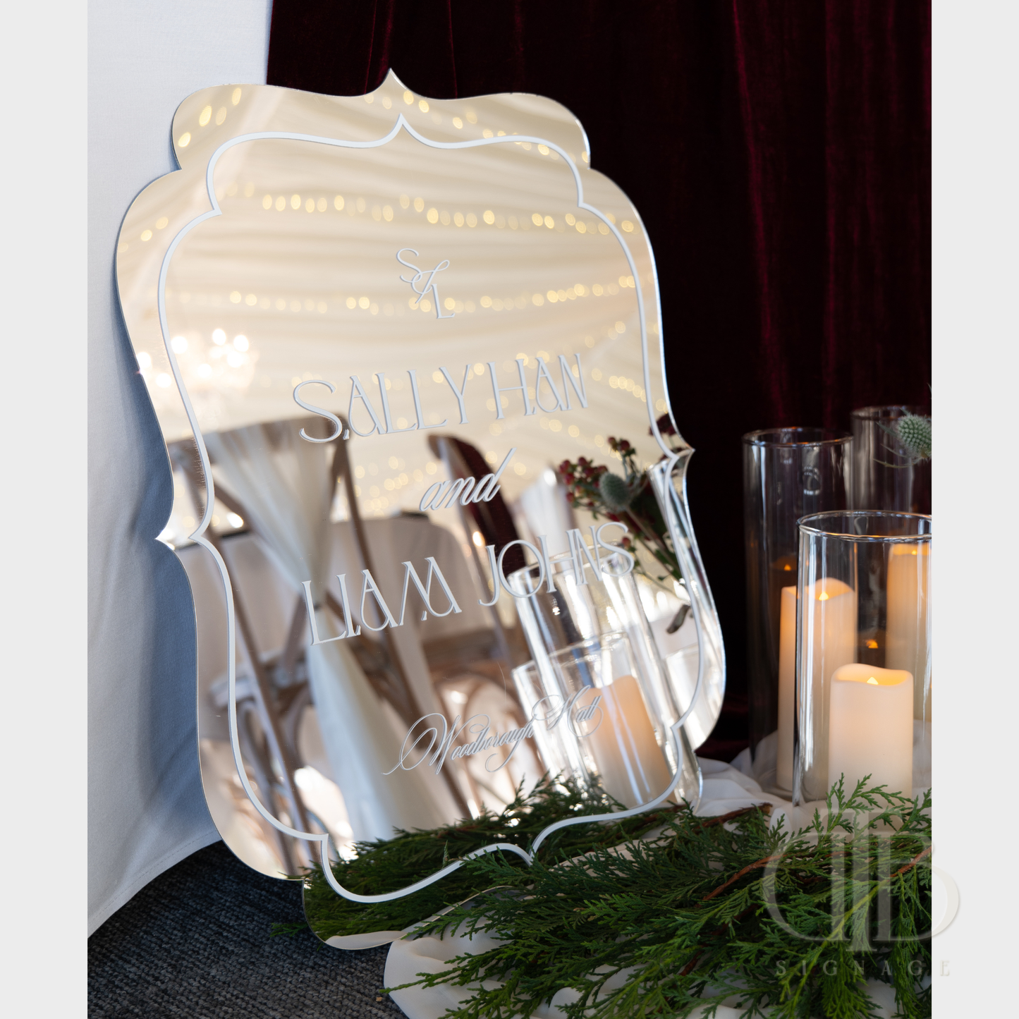 Decorative mirror with personalized text on a table with candles and greenery