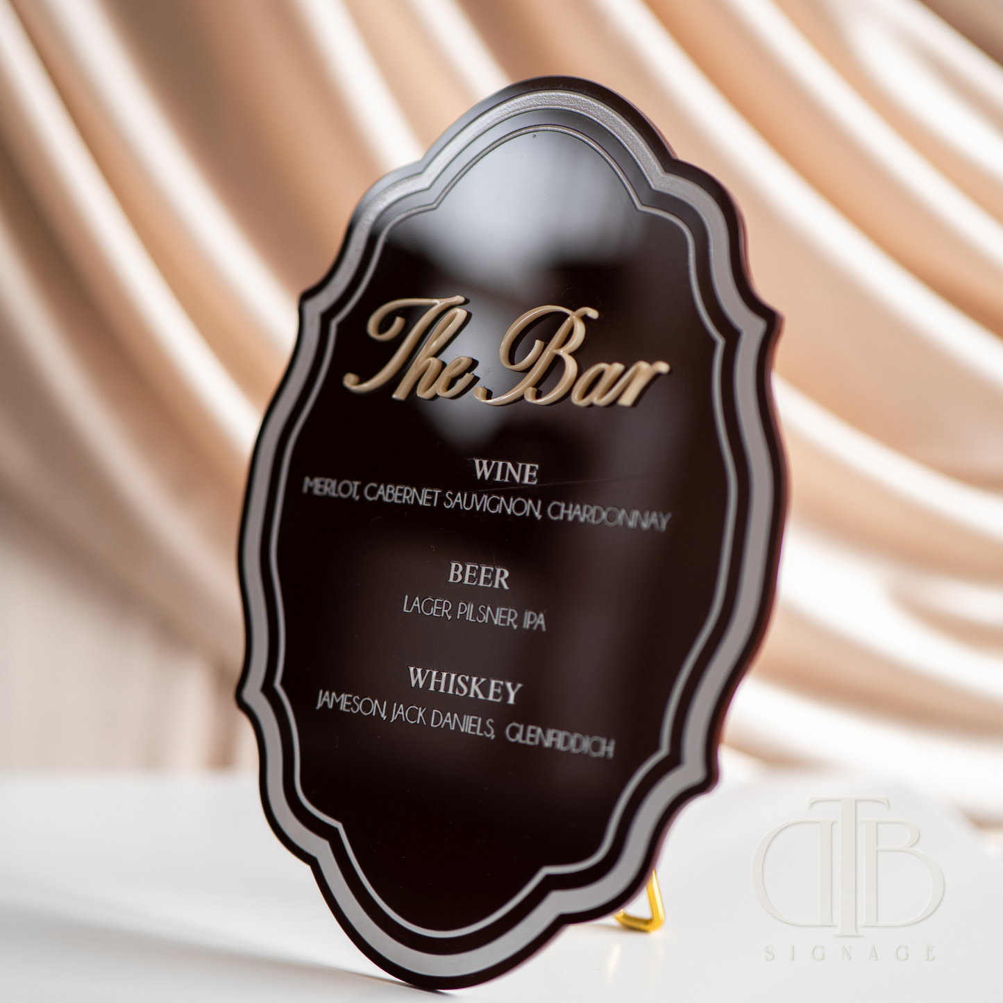 Decorative bar sign with wine, beer, and whiskey options on a draped fabric background