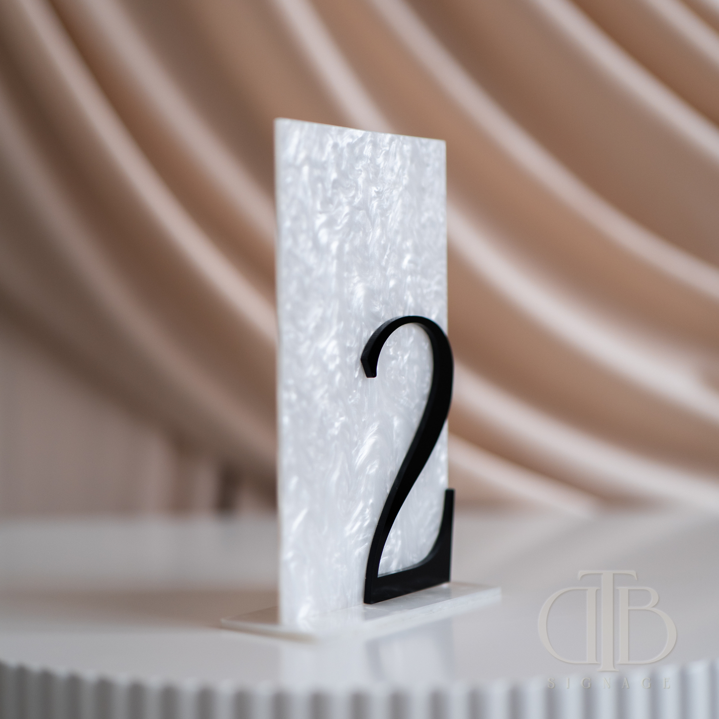 White textured table number with black '2' on a blurred background