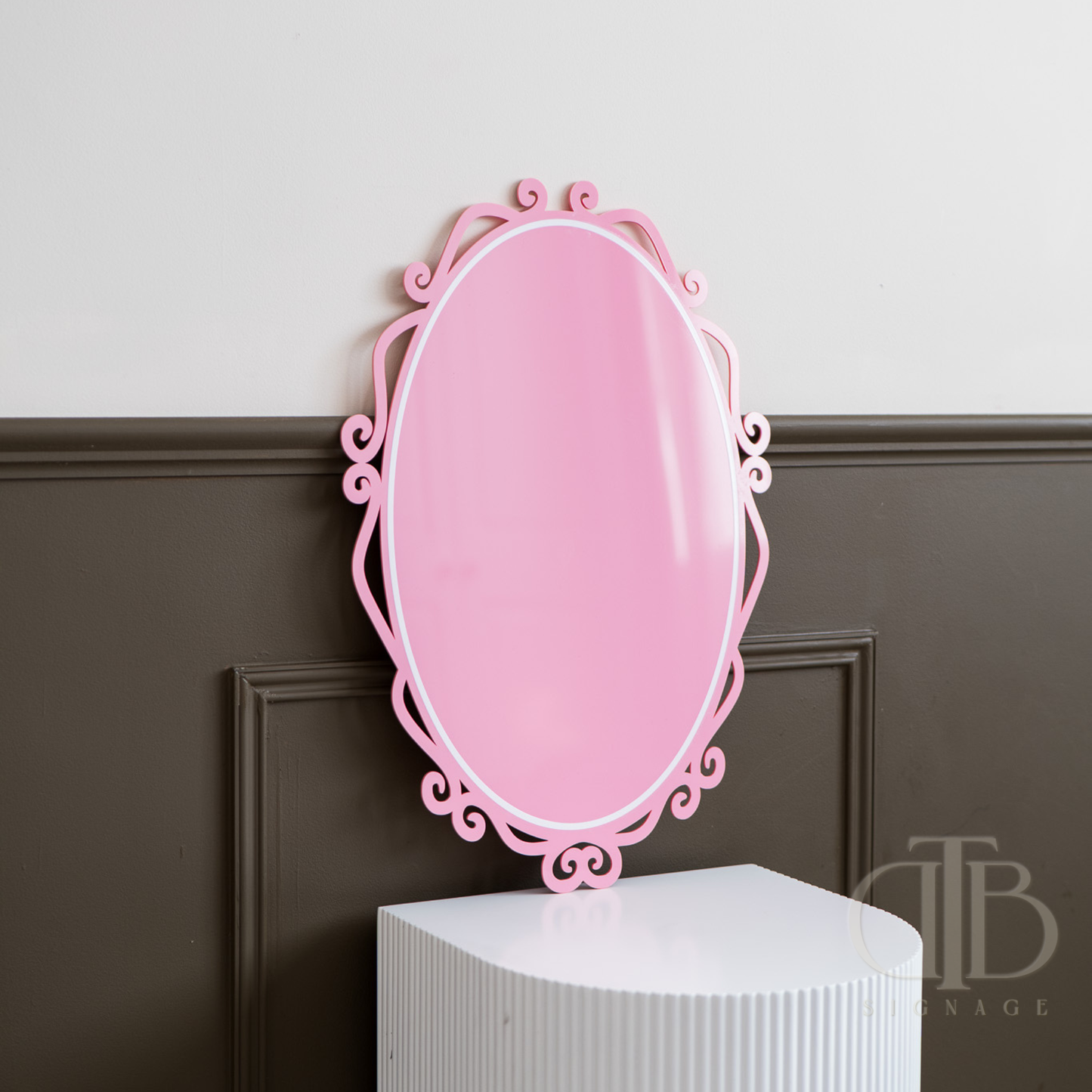 Pink decorative acrylic signage on a white pedestal against a gray wall