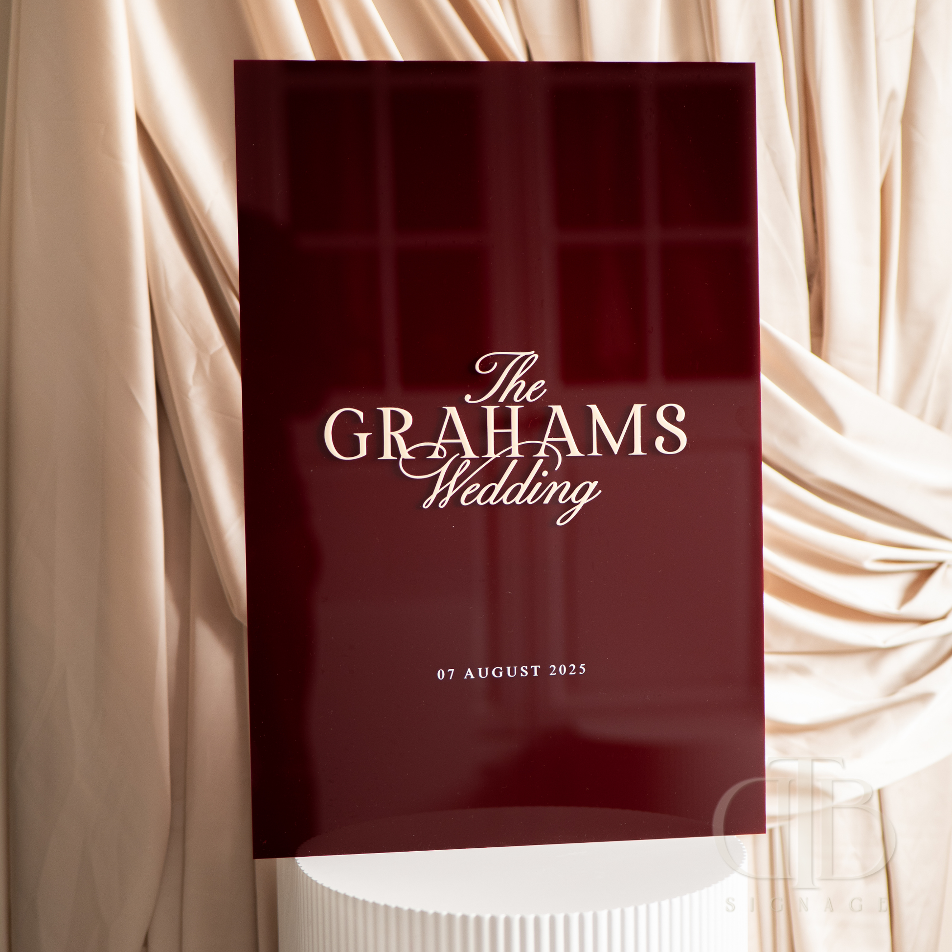 Red wedding program with 'The Grahams Wedding' text against a draped fabric background