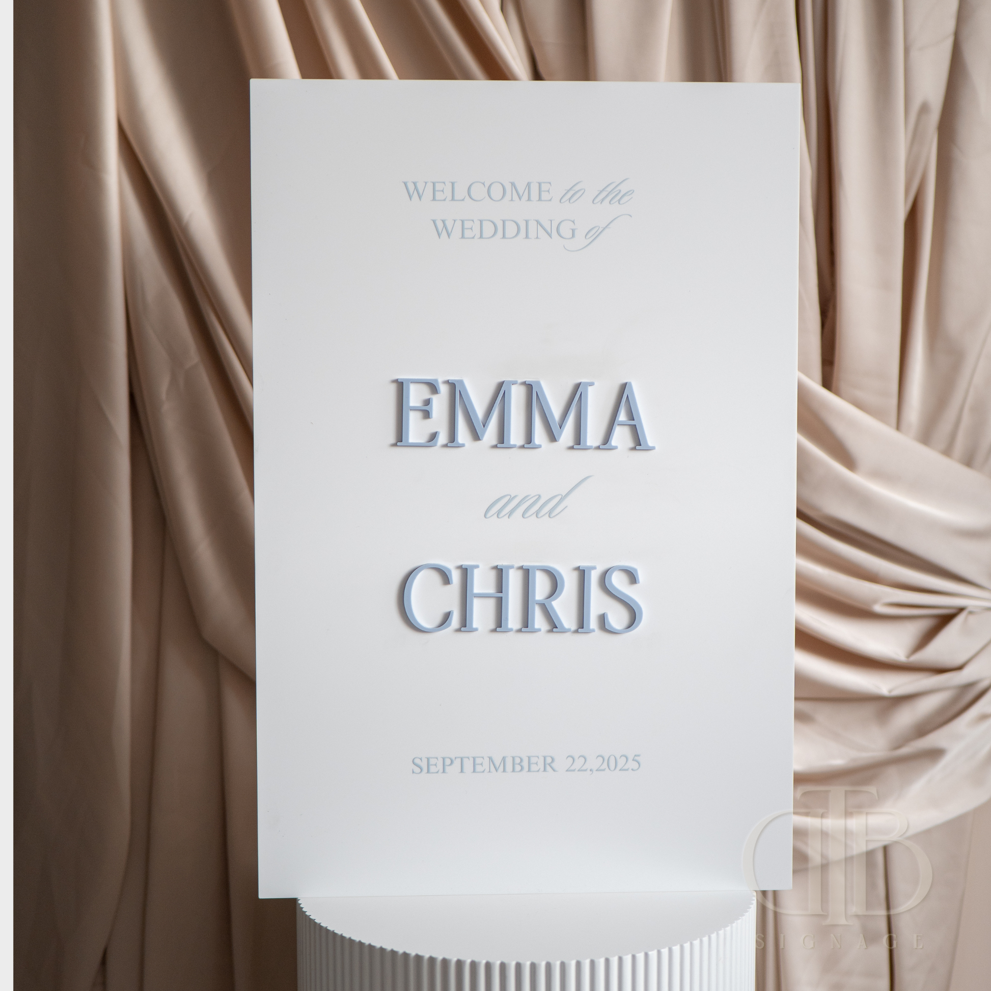 Wedding welcome sign with 'Emma and Chris' on a draped fabric background