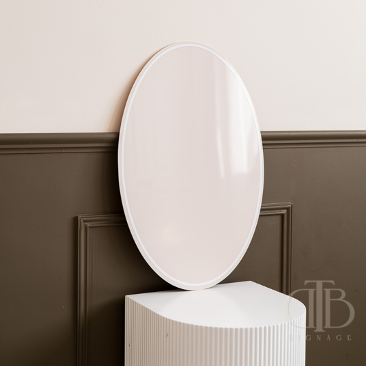 Round white mirror on a pedestal against a wall with wainscoting