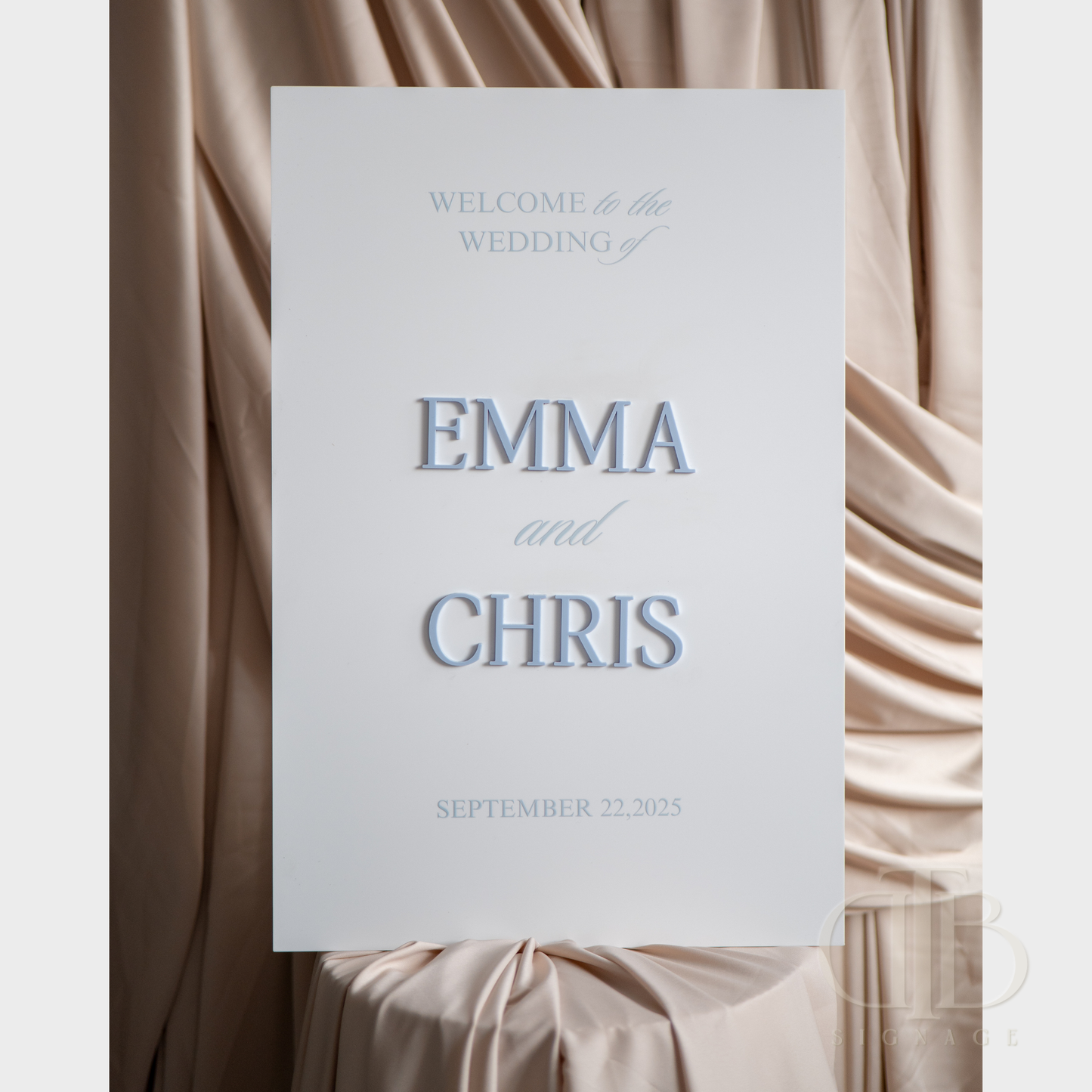 Wedding welcome sign with 'Emma and Chris' on a draped fabric background