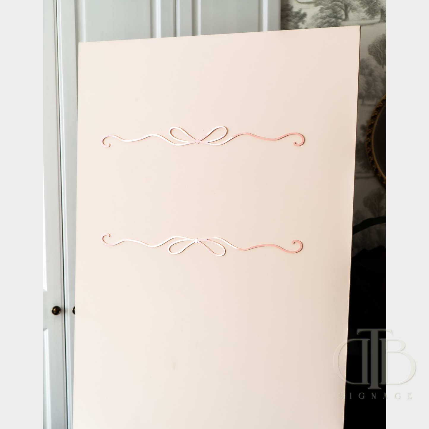 Baby Pink acrylic signage with decorative pink flourishes on a reflective surface