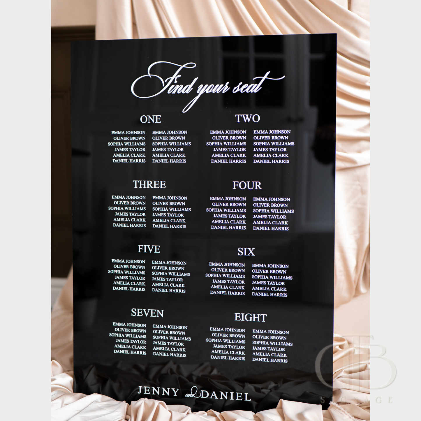 Black seating chart with white text on a decorative background