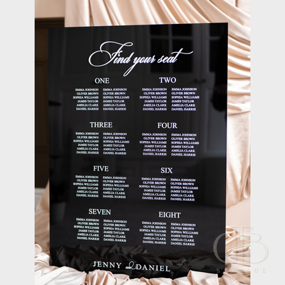 Black seating chart with white text on a decorative background