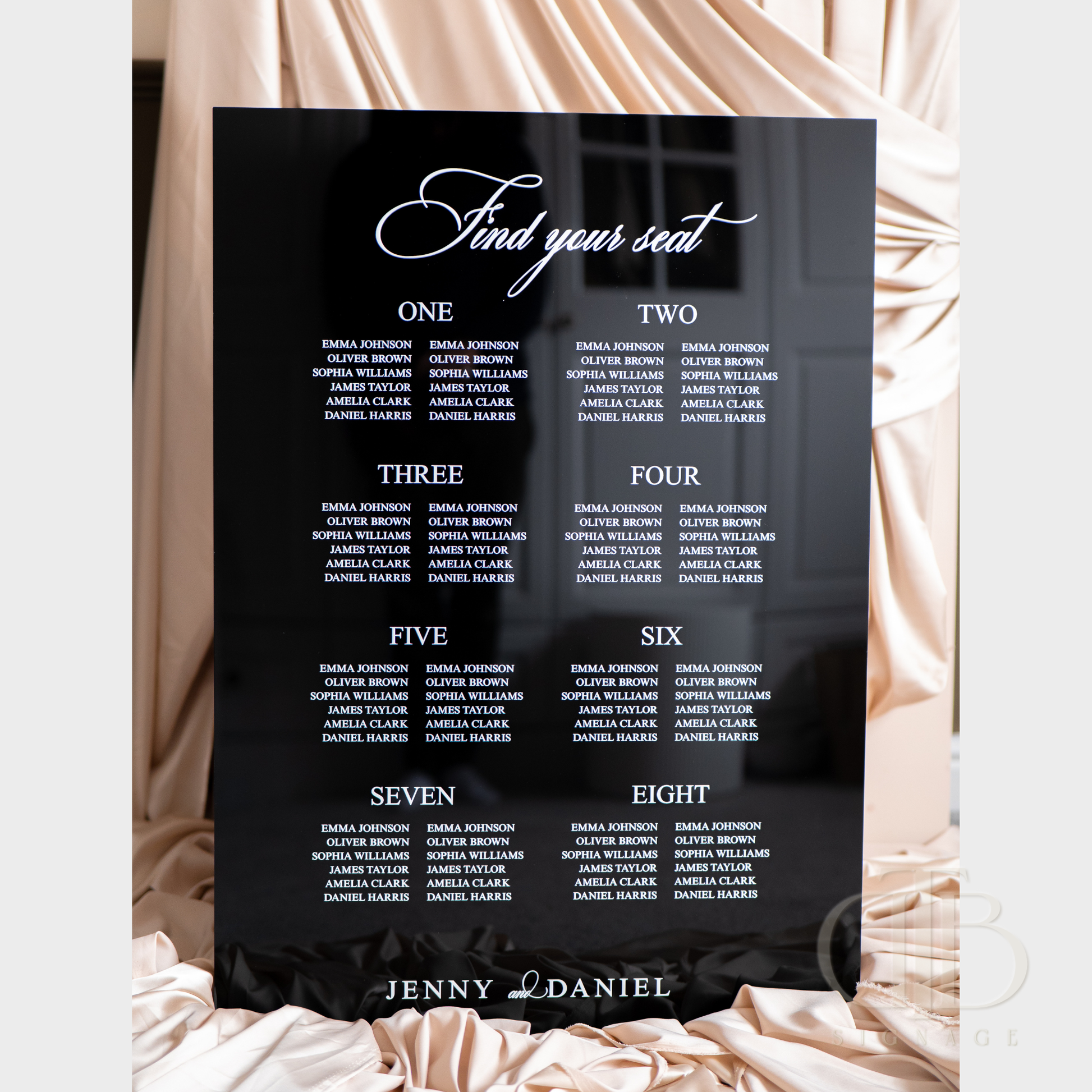 Black seating chart with white text on a decorative background