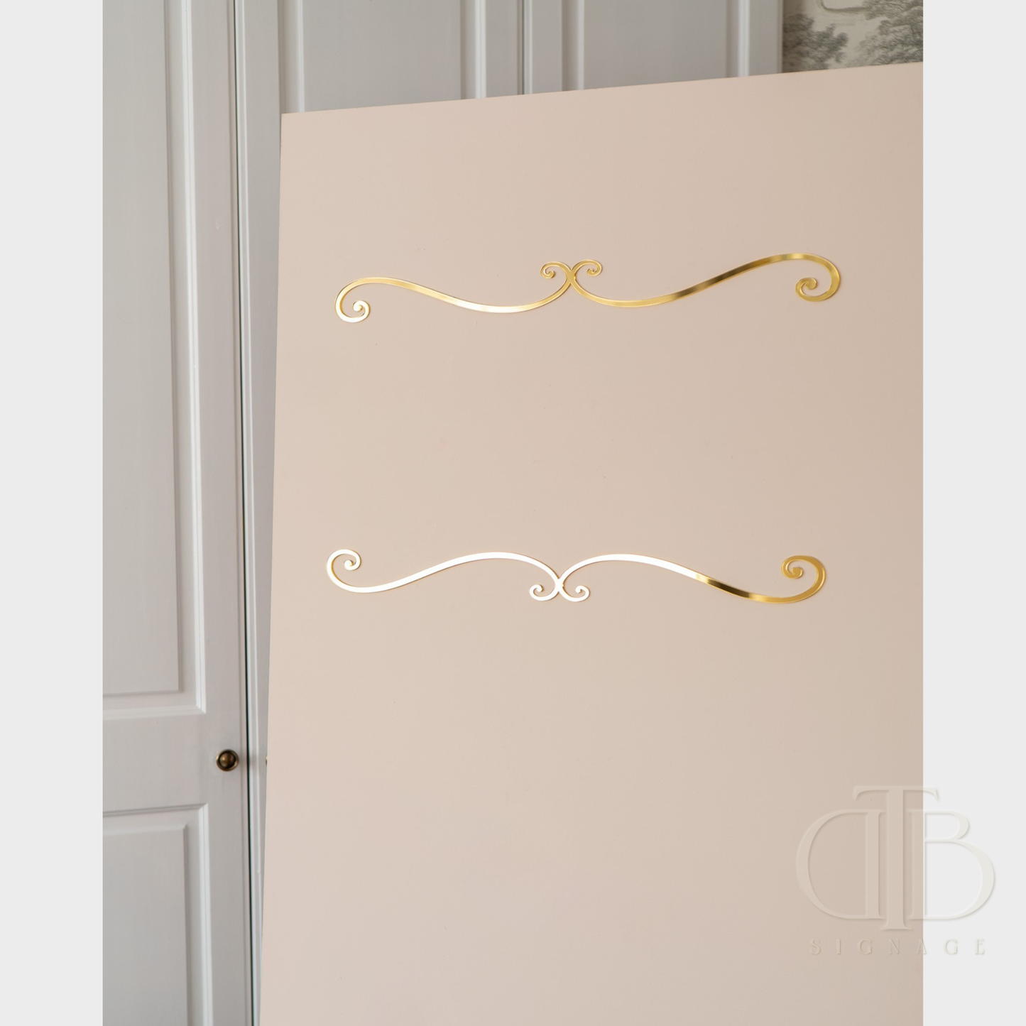 Decorative gold and white swirl designs on a beige wall.