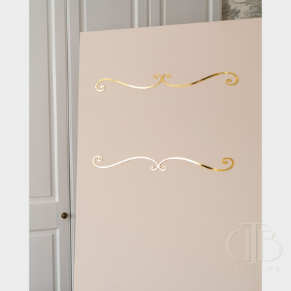 Decorative gold and white swirl designs on a beige wall.