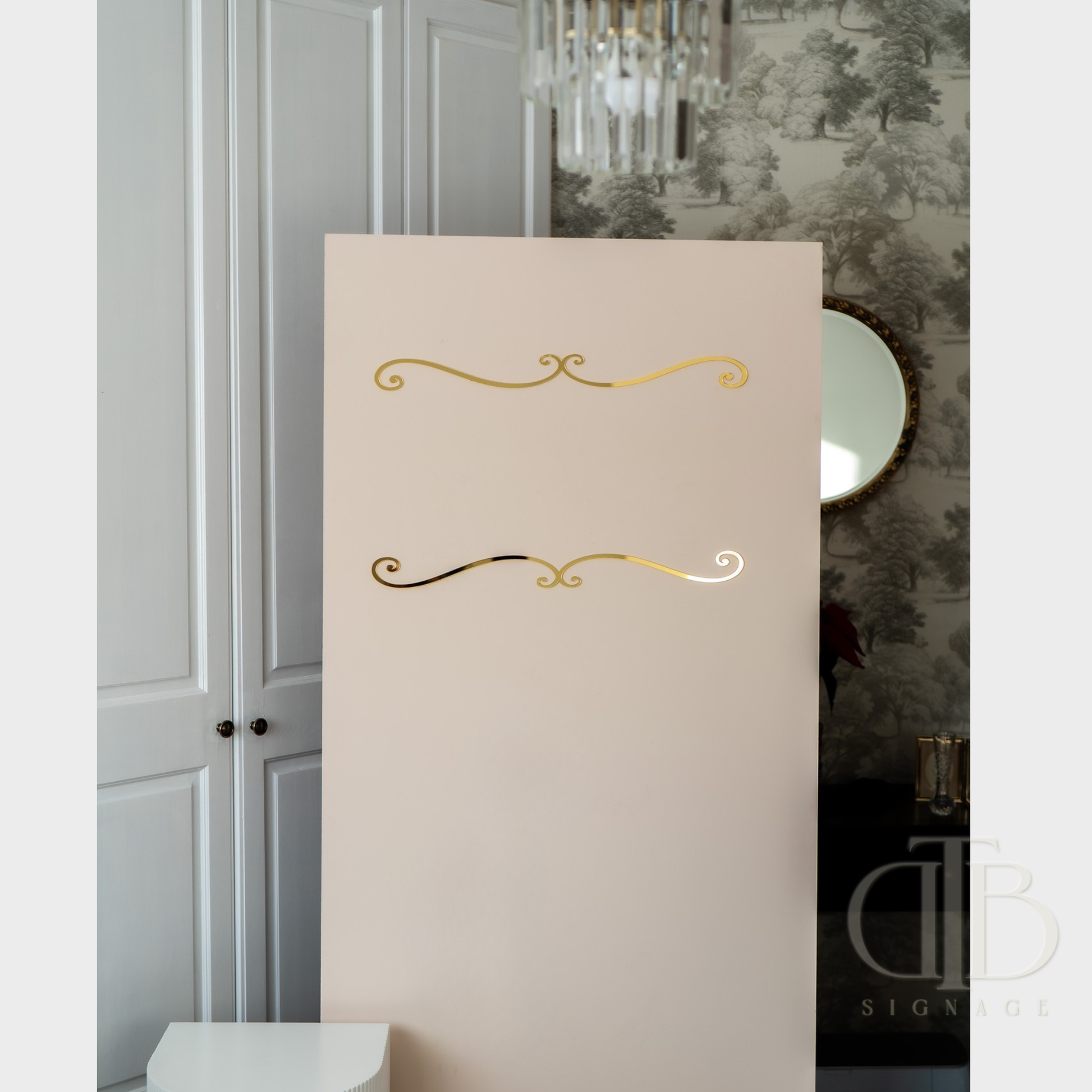 Decorative panel with gold embellishments on a neutral background, featuring a chandelier and mirror.