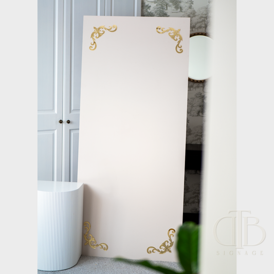 Decorative white panel with gold accents on a wall next to a white cabinet.