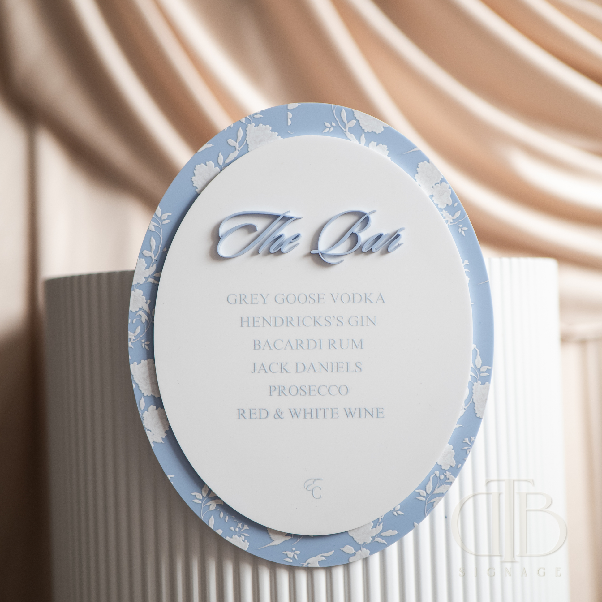 Round cocktail menu with blue decorative border and white text against a neutral background
