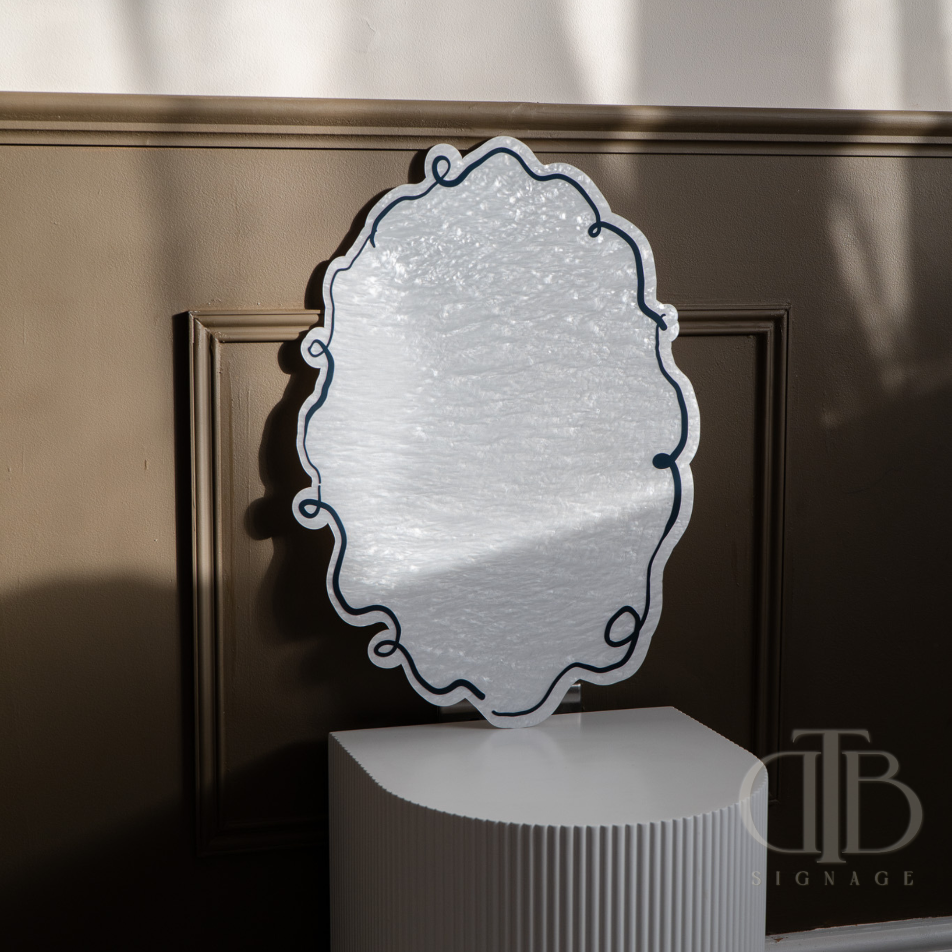 Decorative mirror with textured surface on a stand against a dark background