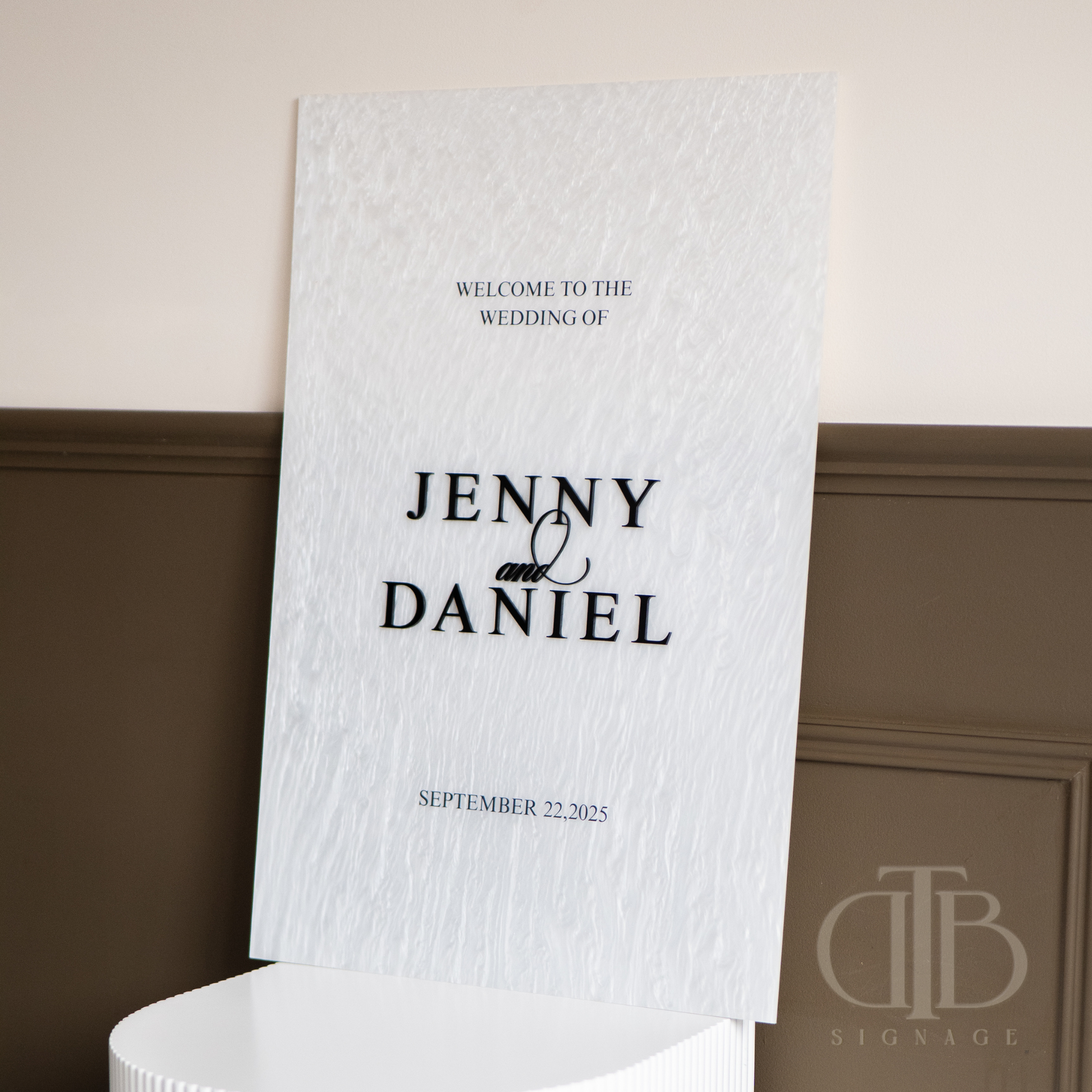 Wedding welcome sign with 'Jenny and Daniel' on a decorative wall.