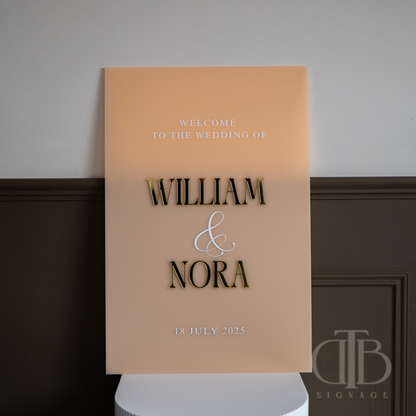 Wedding welcome sign with 'William & Nora' on a stand against a plain background