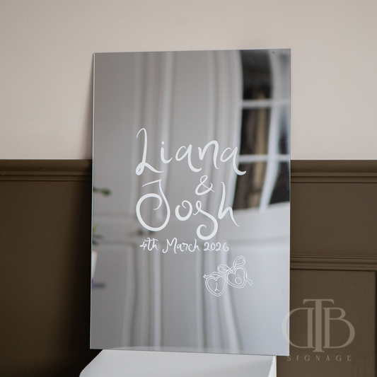 Decorative mirror with 'Liana & Josh' and date on a wall.