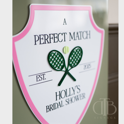 Shield-shaped sign with tennis racket design and text for a bridal shower.
