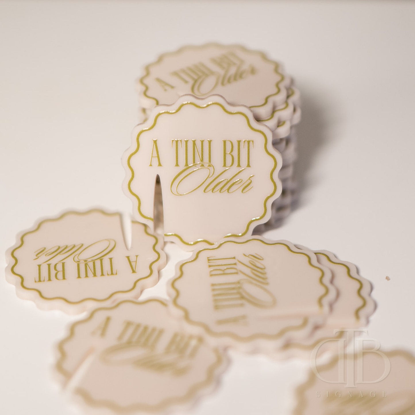 Round stickers with 'A Tini Bit Older' text on a light background