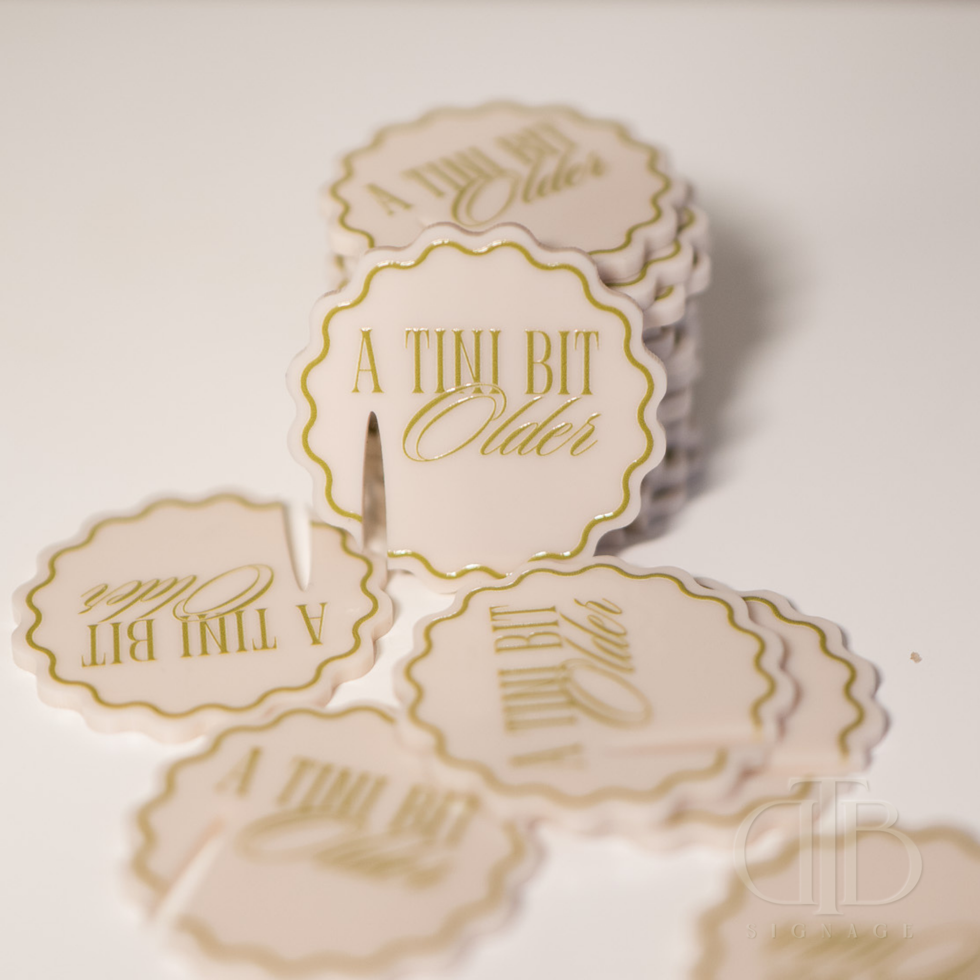Round stickers with 'A Tini Bit Older' text on a light background