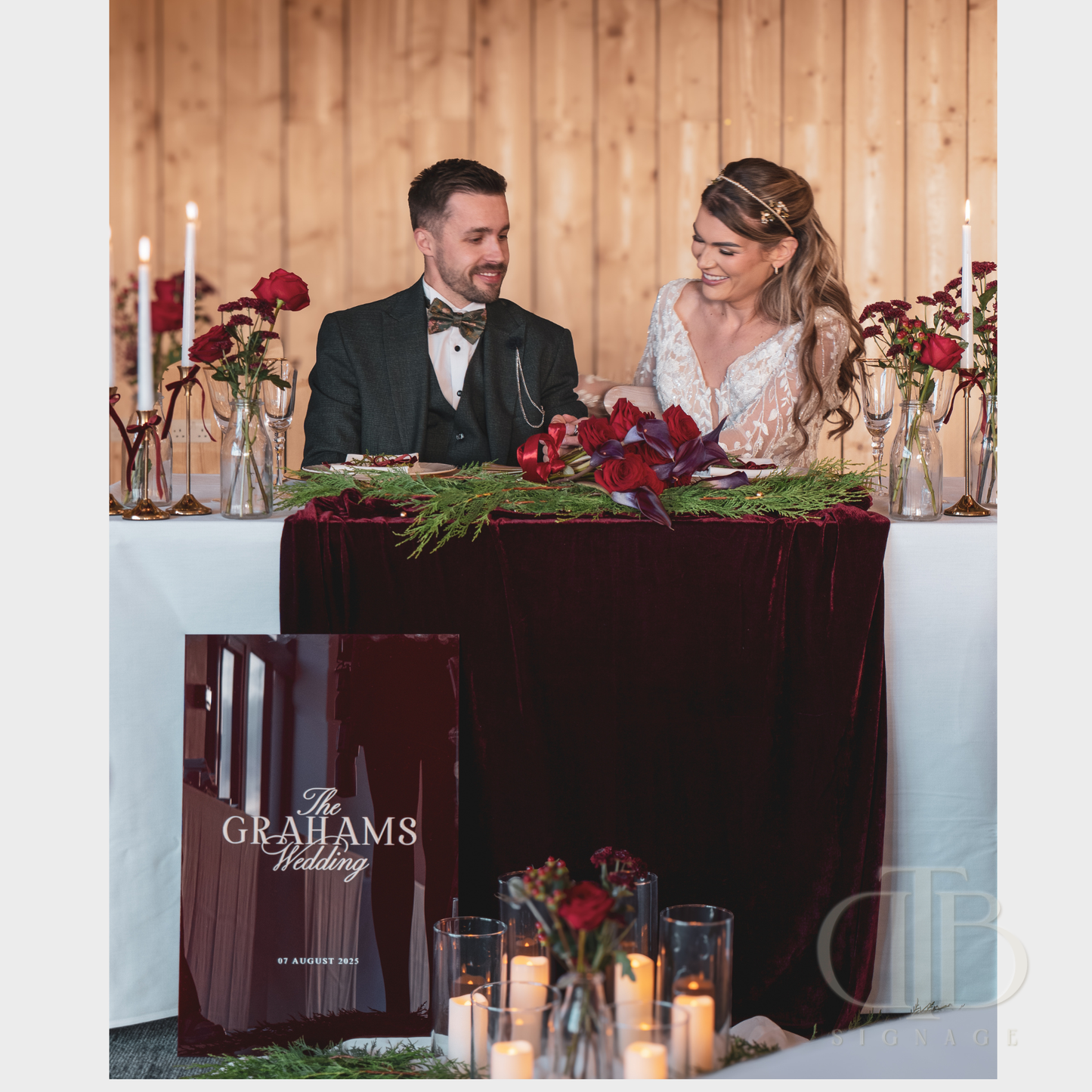 Bride and groom sitting at a decorated wedding table with 'The Grahams Wedding' sign.