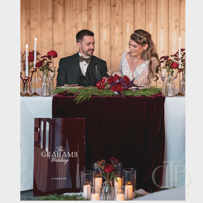 Bride and groom sitting at a decorated wedding table with 'The Grahams Wedding' sign.