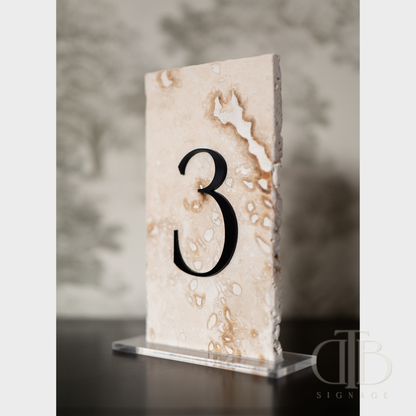 Marble-like table number '3' on a stand with a blurred background