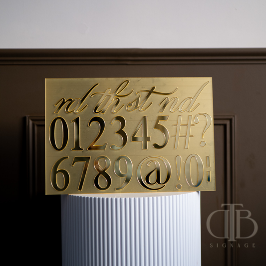 Gold sign with numbers and symbols on a white column against a dark background