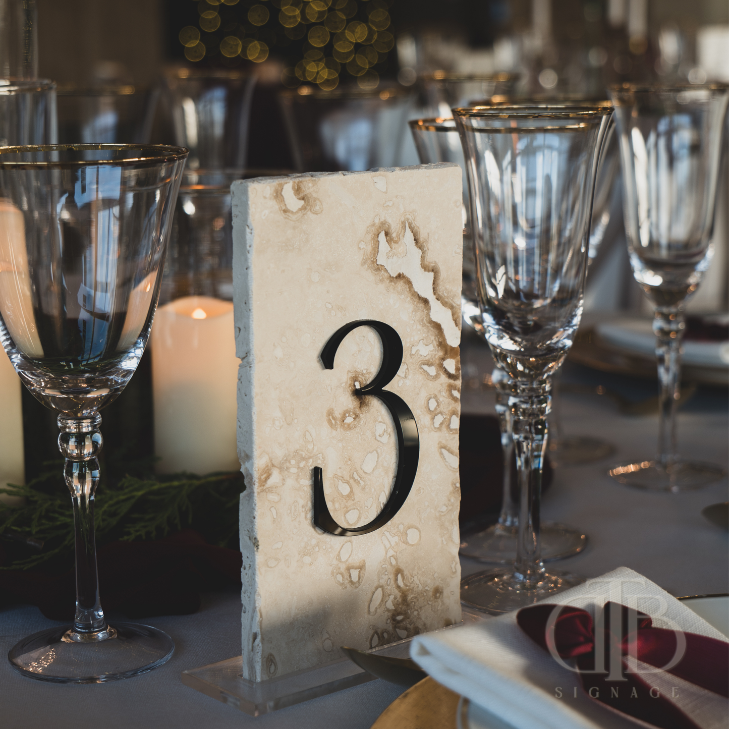 Table number '3' on a decorative stand with wine glasses and candles in the background