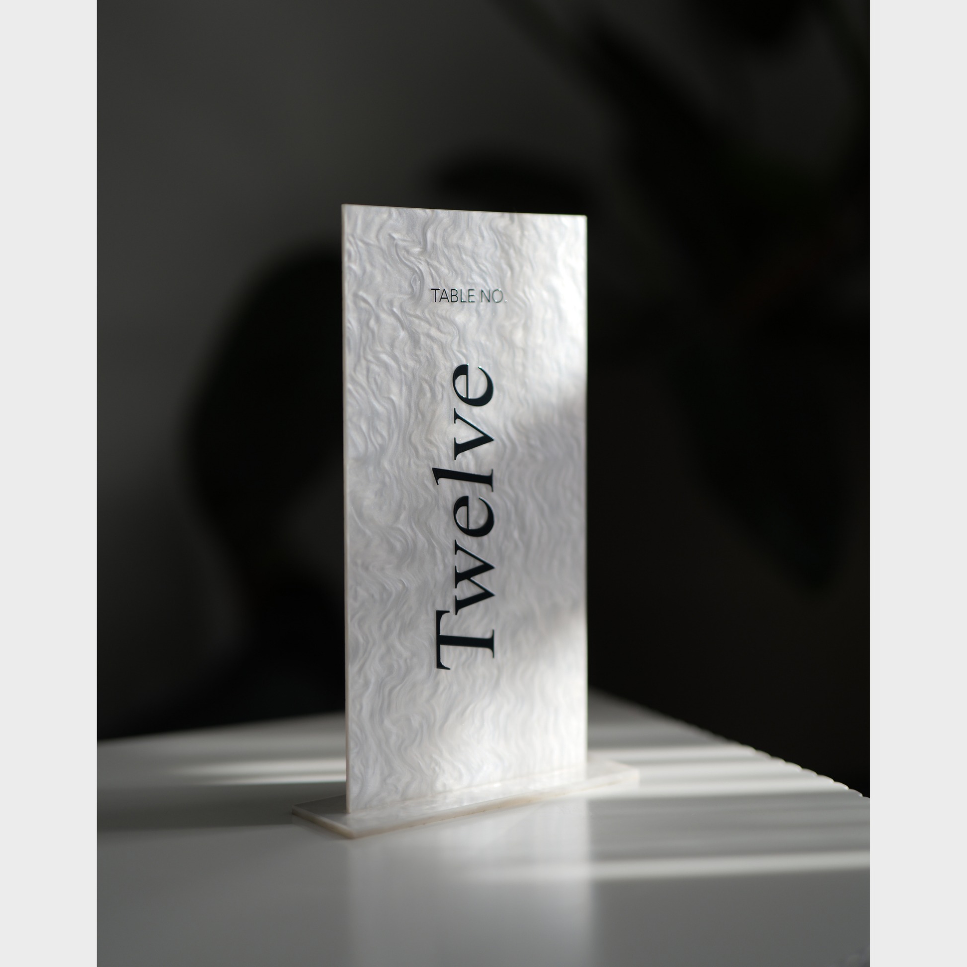 Marble-textured table number card with 'Twelve' on a dark background