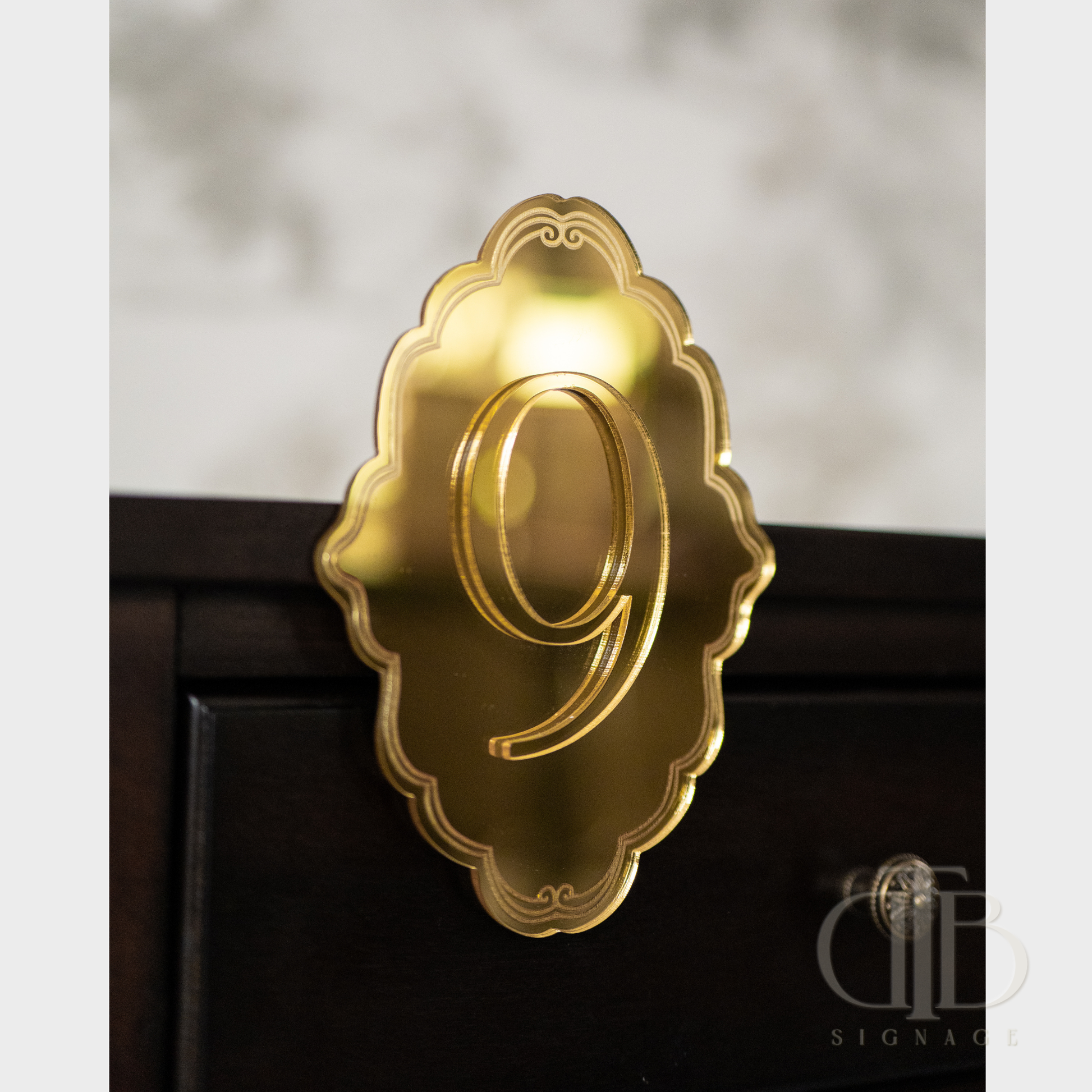 Gold number '9' on a decorative plaque against a blurred background