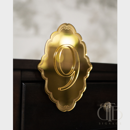 Gold number '9' on a decorative plaque against a blurred background