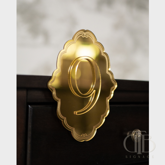 Gold number '9' on a decorative plaque against a blurred background
