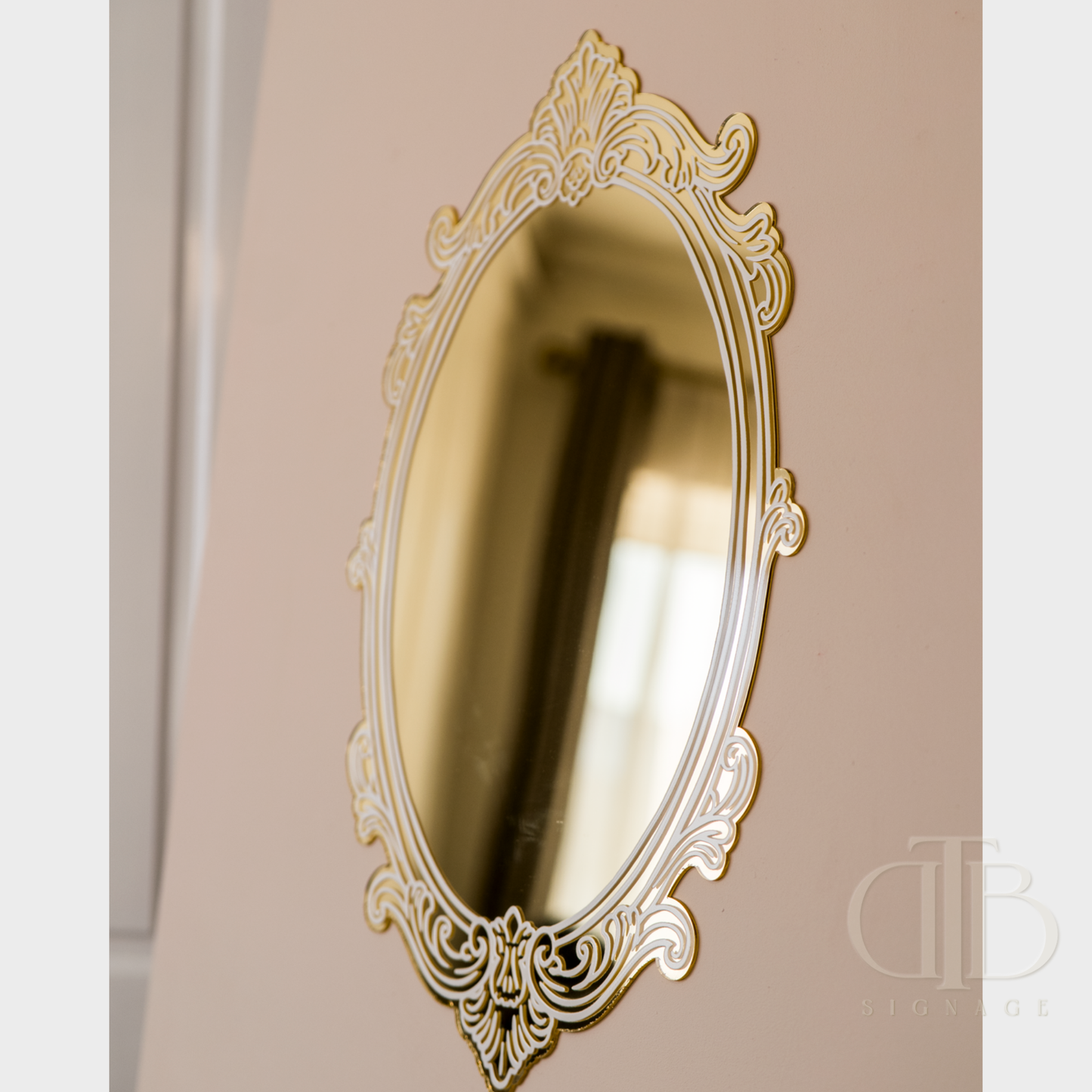 Decorative gold mirror with intricate patterns on a beige wall.