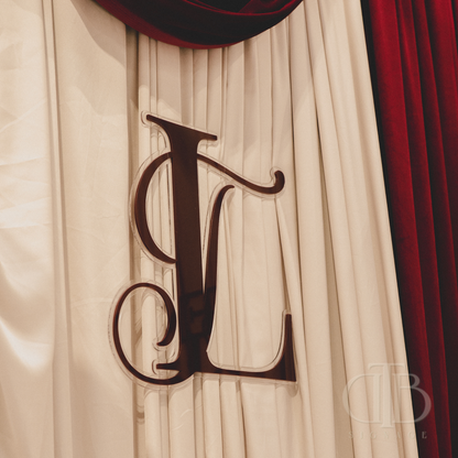 Decorative letter 'L' on a textured beige and red fabric background