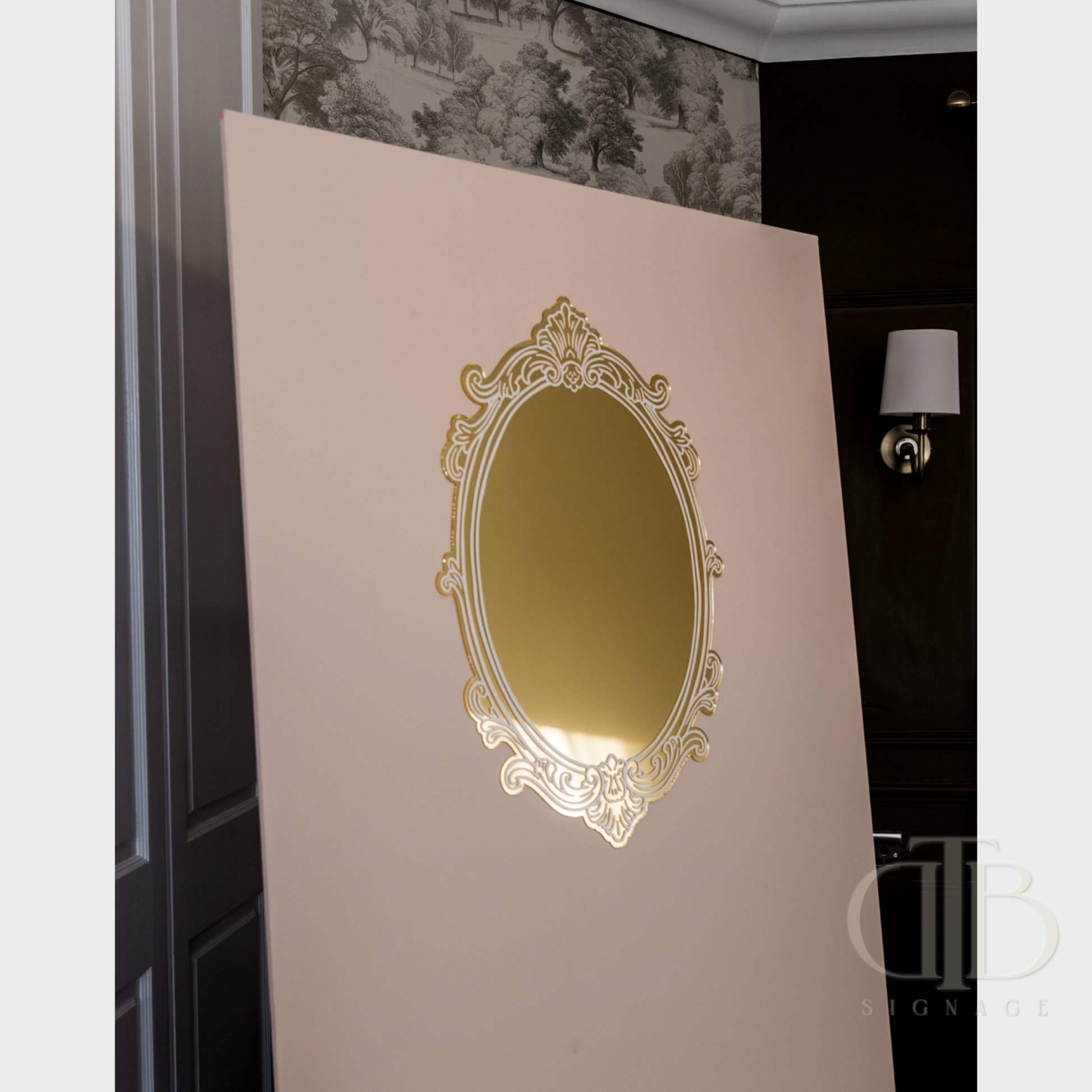 Decorative gold mirror on a beige wall with a dark room background