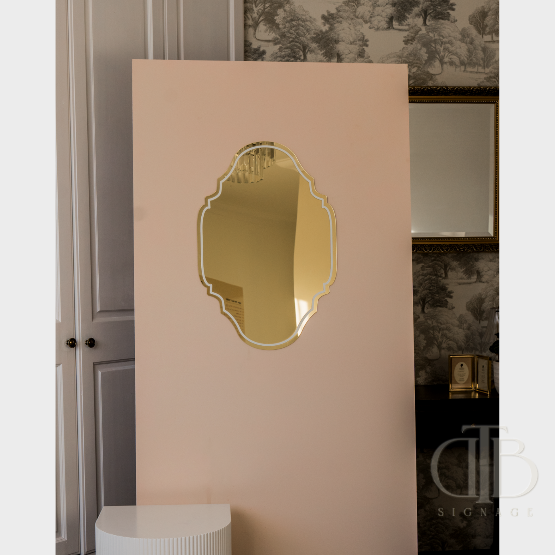 Decorative mirror on a beige wall with a subtle patterned wallpaper background