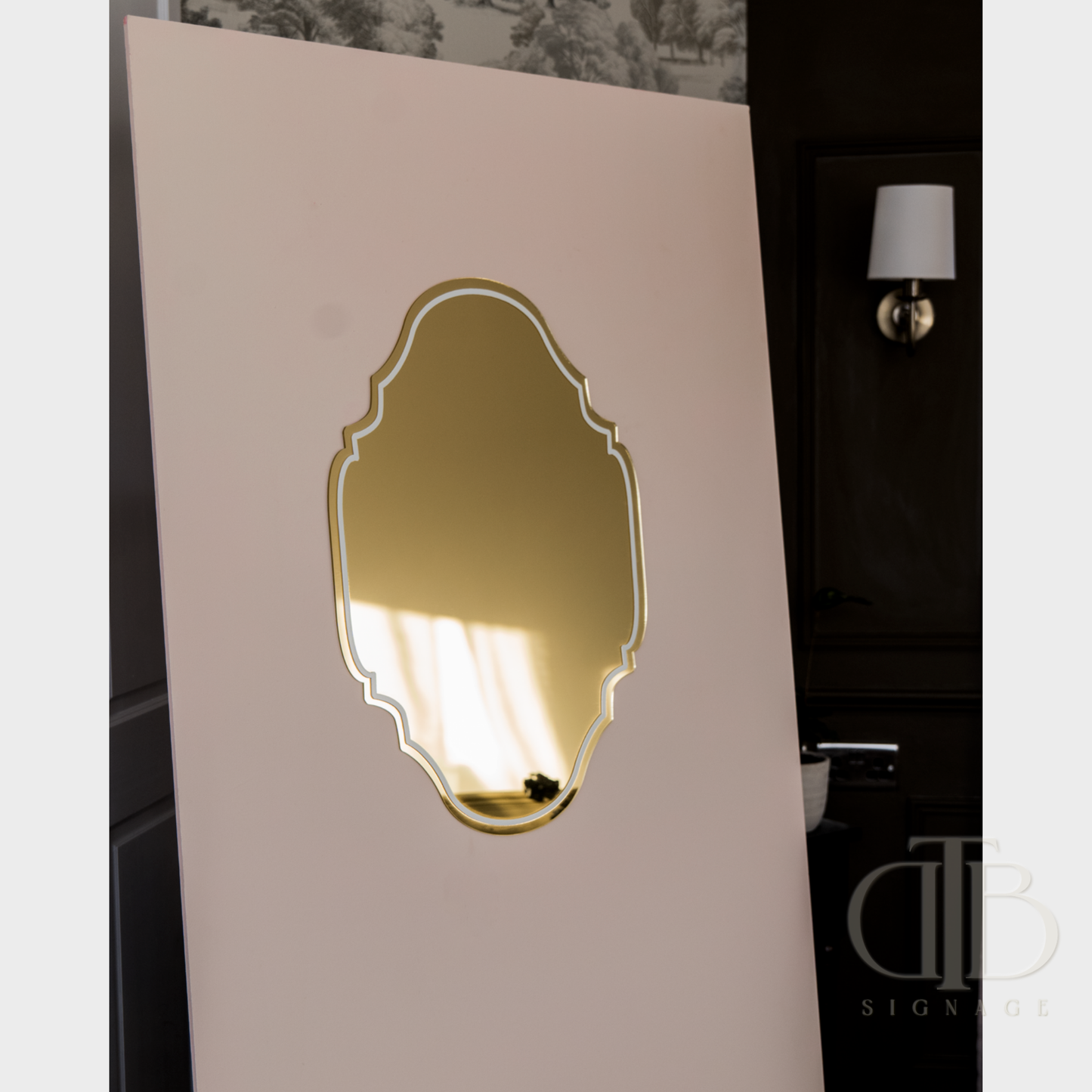 Decorative wall mirror with gold frame on a beige wall.