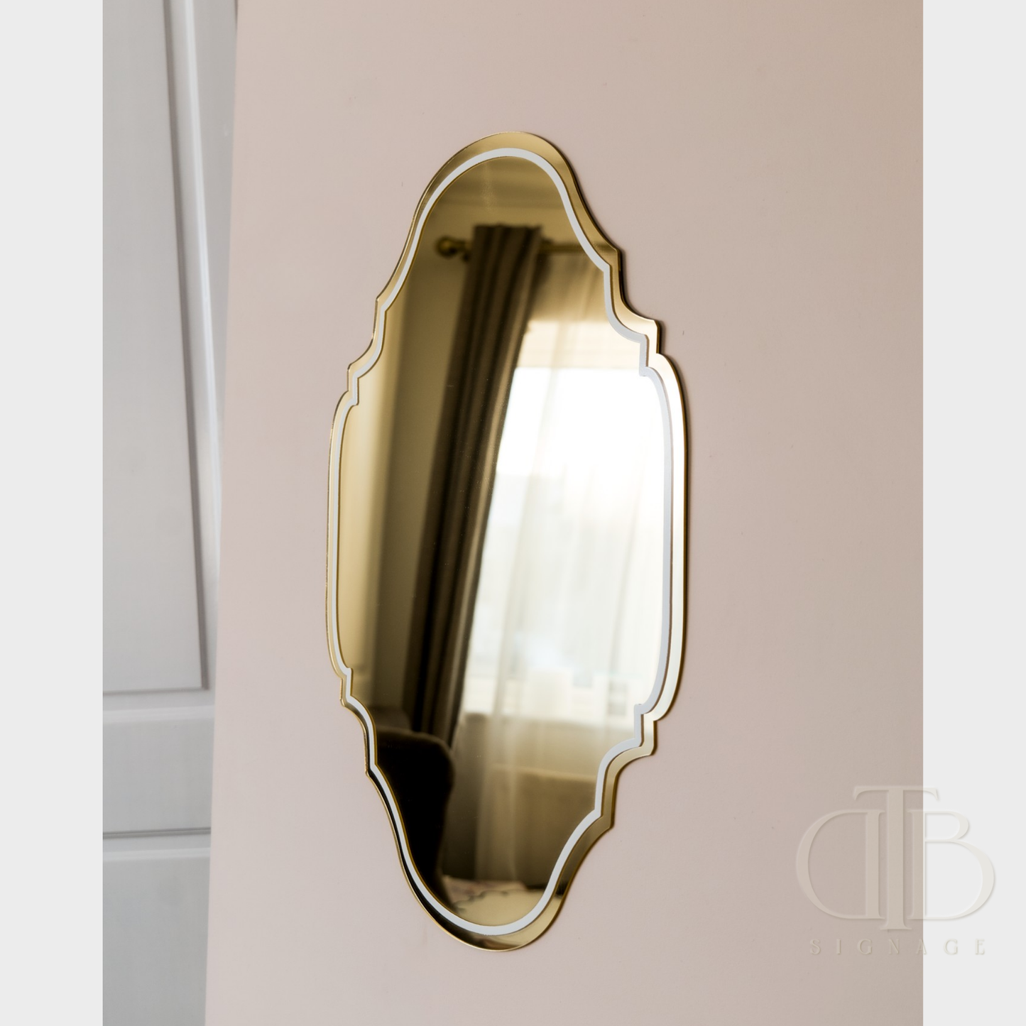 Decorative wall mirror with a gold frame on a beige wall