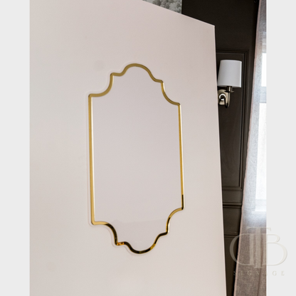 Decorative wall mirror with gold frame on a white wall
