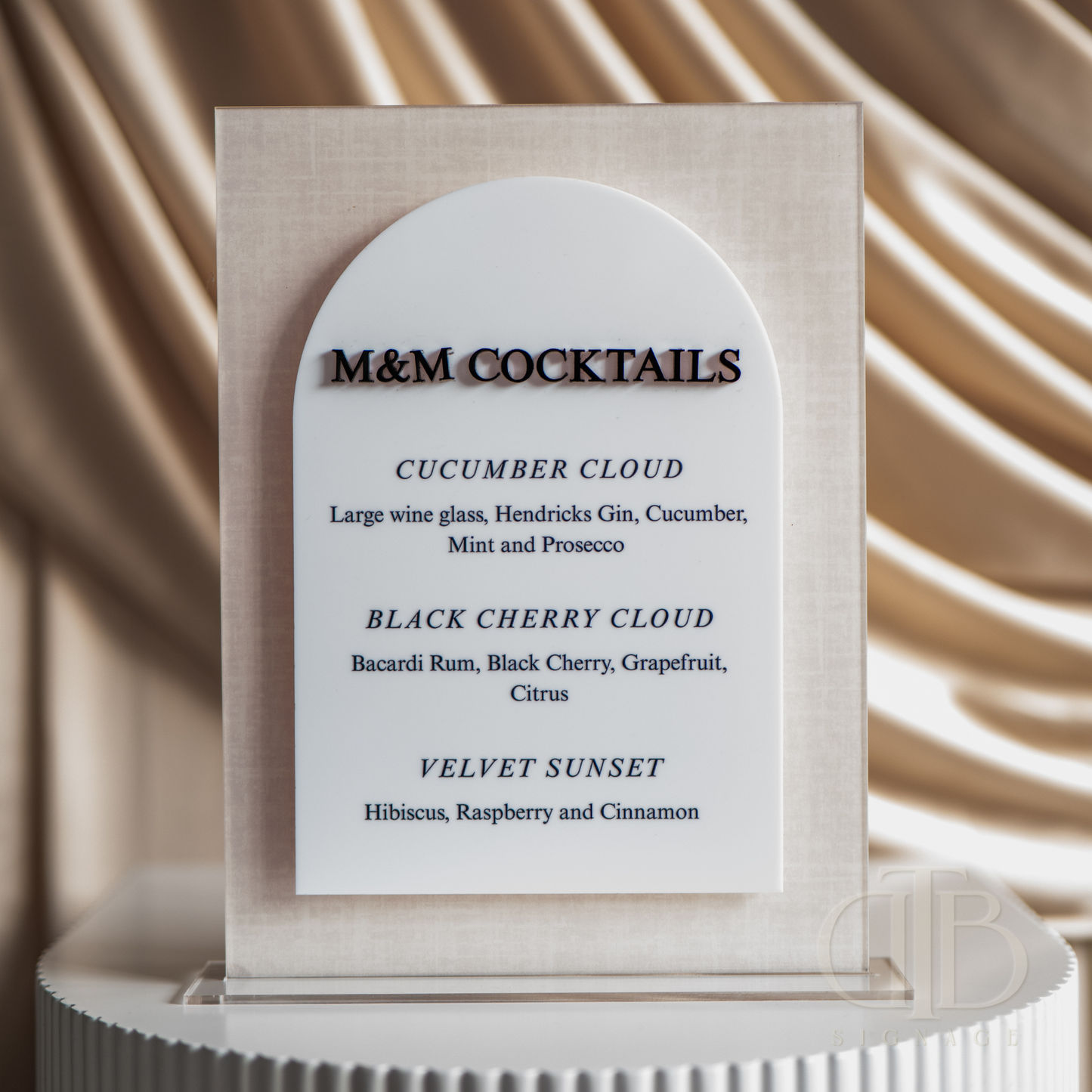 M&M Cocktails menu on a decorative stand with a beige background