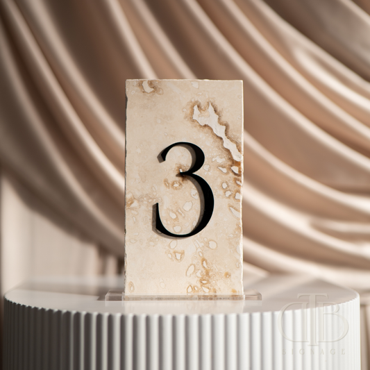 Natural stone table number '3' on a white pedestal with a draped fabric background