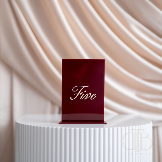 Red card with 'Five' on a white pedestal against a beige curtain background