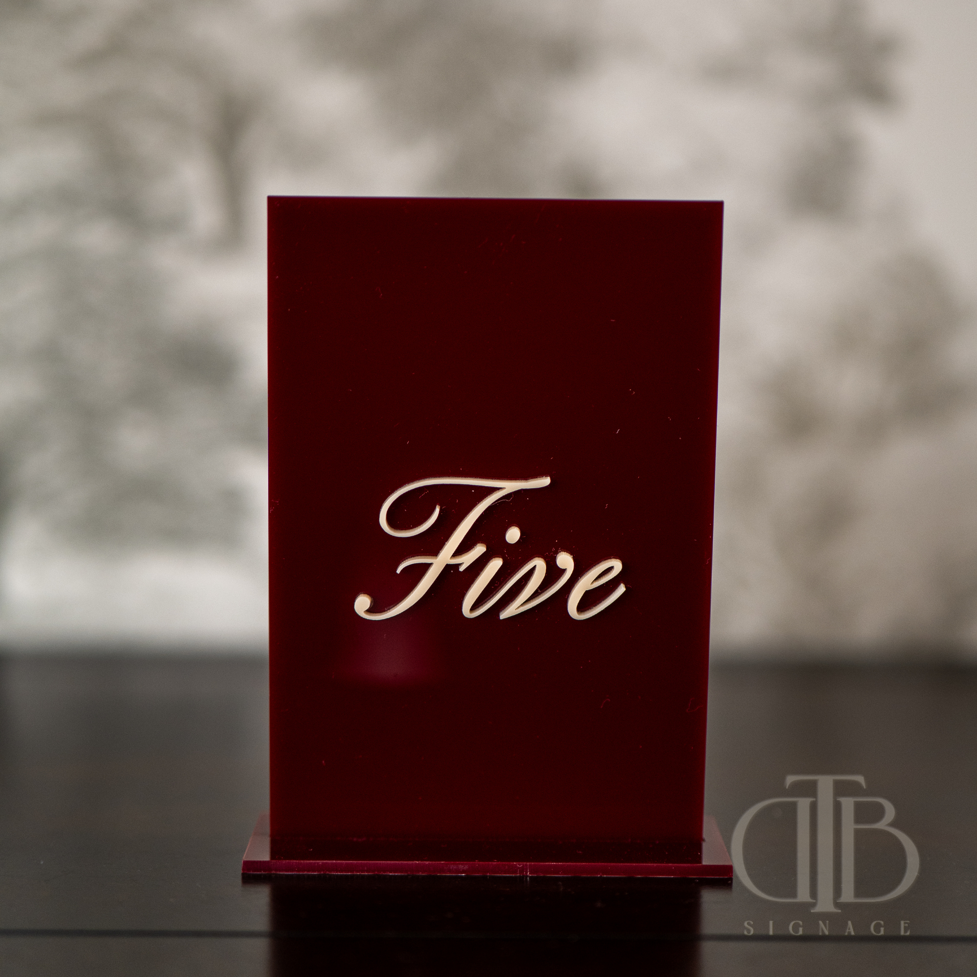 Red card with 'Five' on a white pedestal against a beige curtain background