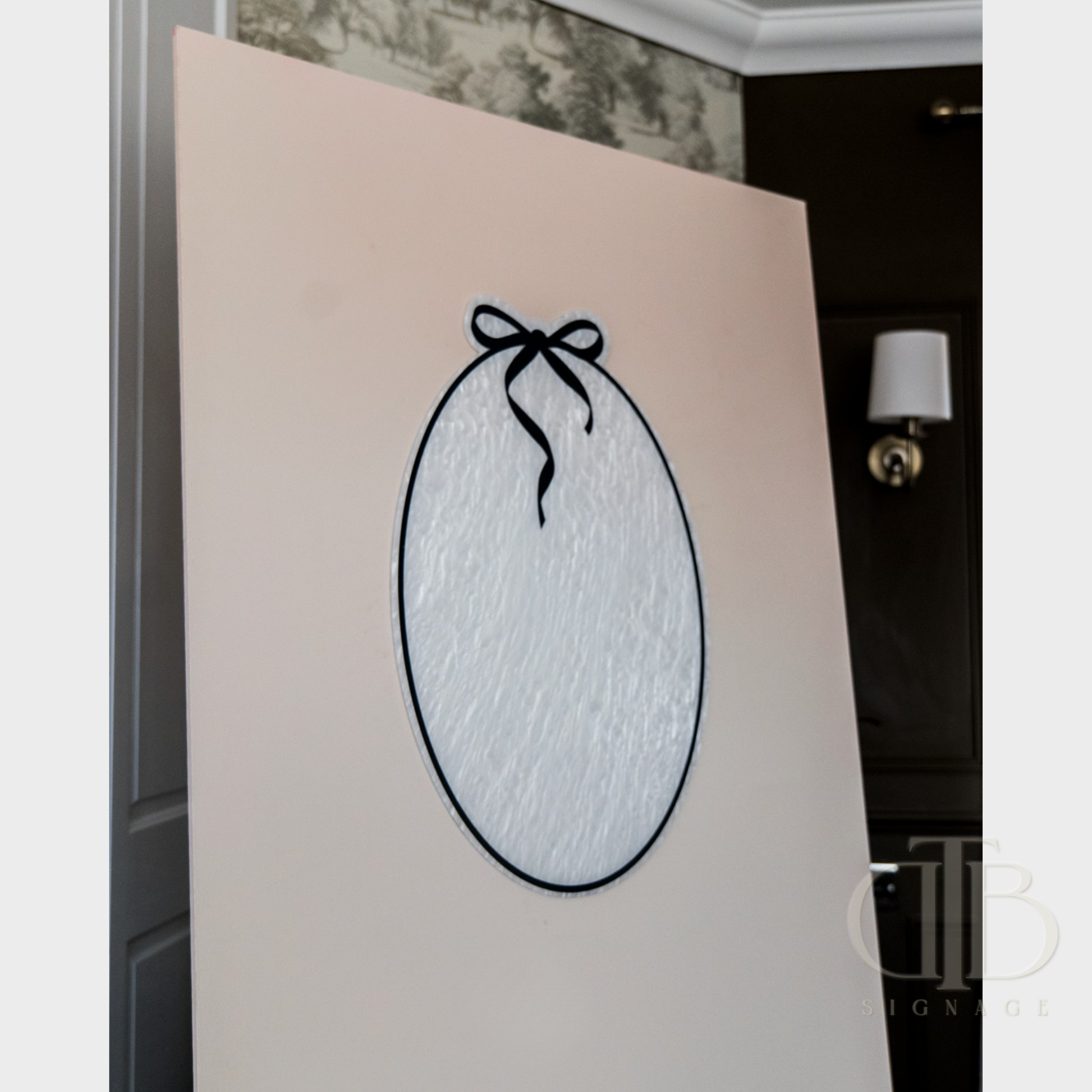 Decorative wall art with a black bow design on a beige background