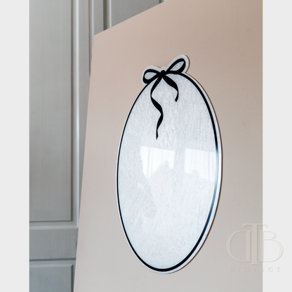 Decorative mirror with a black bow on a beige wall