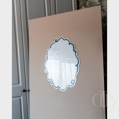 Decorative mirror with intricate design on a light-colored wall.